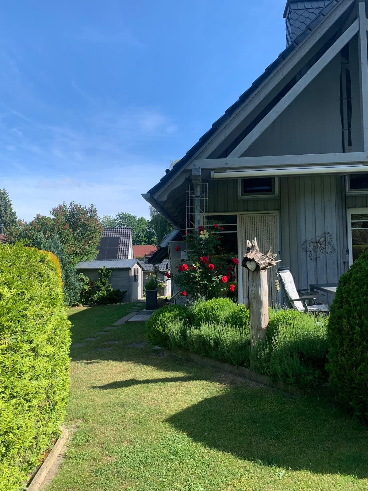 Gartenweg an der Hauswand entlang, mit Rosen und Blick zum Gartenhaus