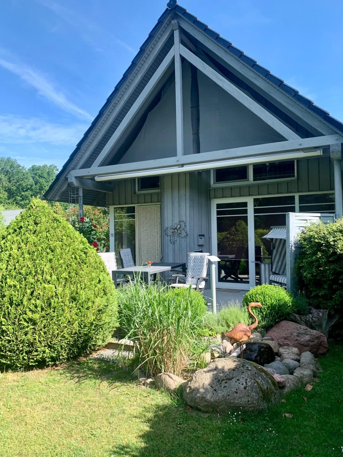 Giebelseite des Ferienhauses mit überdachter Terrasse und Gartenteich
