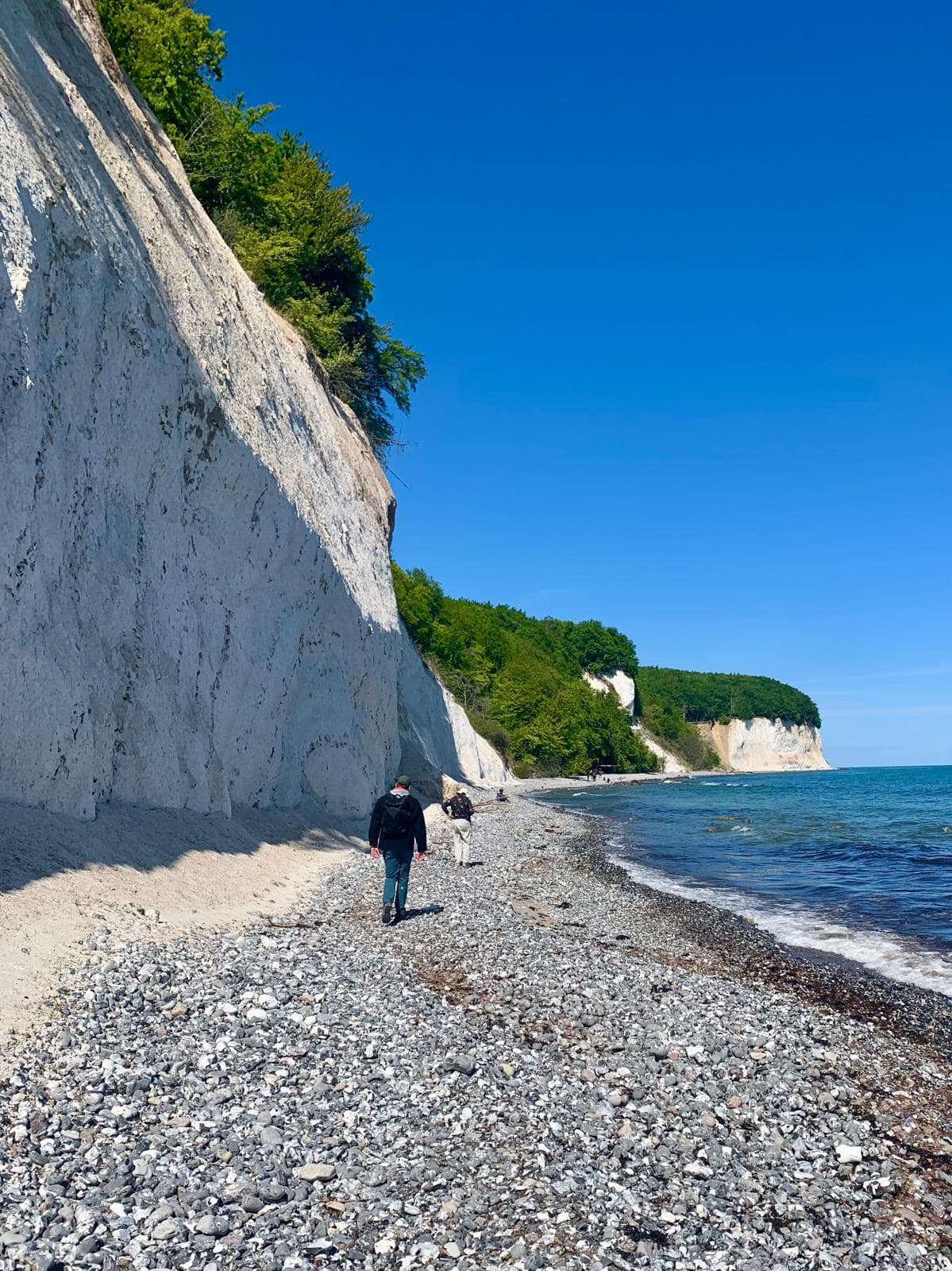 Spaziergänger am Feuersteinstrand unter der hohen Kreidewand