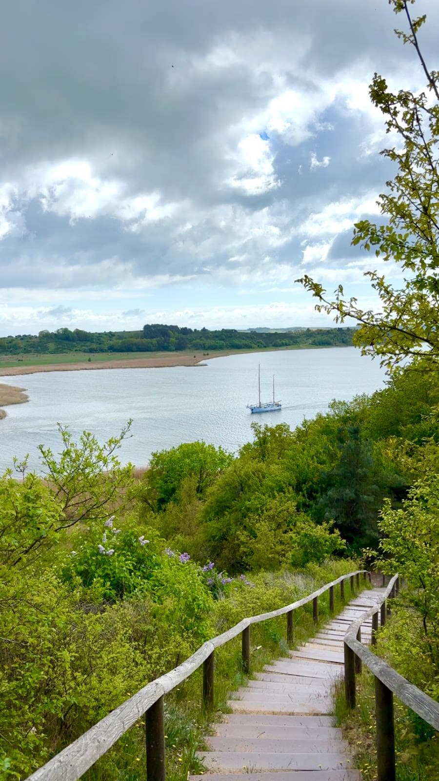 Holztreppe hinunter zum Bodden, ein Segelboot in der Bucht
